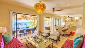 A spacious living area with a dining set, a sofa, and a coffee table. - Villa Encantada by Coco B Isla (Isla Mujeres)