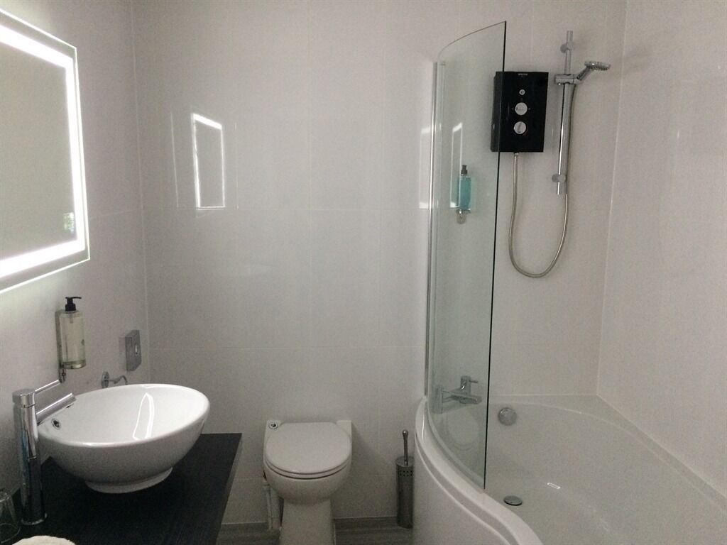 A bathroom with a white sink, toilet, and glass-enclosed shower.