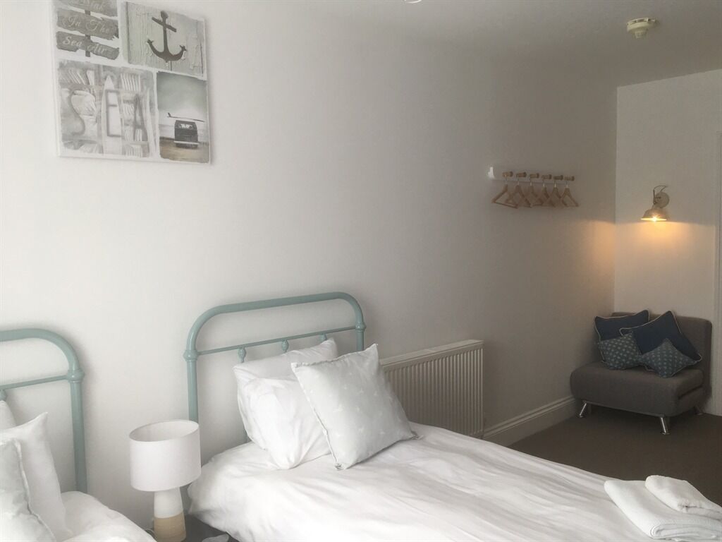 A hotel room with a bed, a nightstand, a lamp, a radiator, a seating area, and a wall with nautical-themed decor.