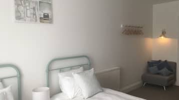 A hotel room with a bed, a nightstand, a lamp, a radiator, a seating area, and a wall with nautical-themed decor.