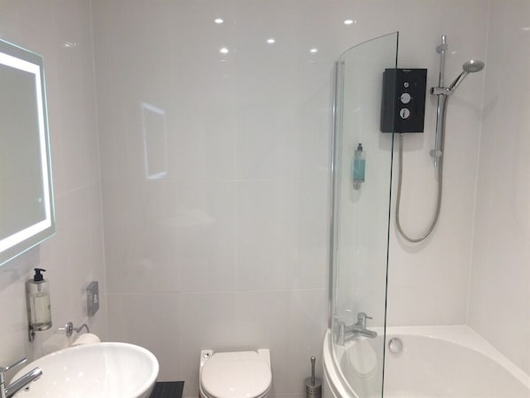 A modern bathroom with a glass-enclosed shower, a white sink, and a toilet.