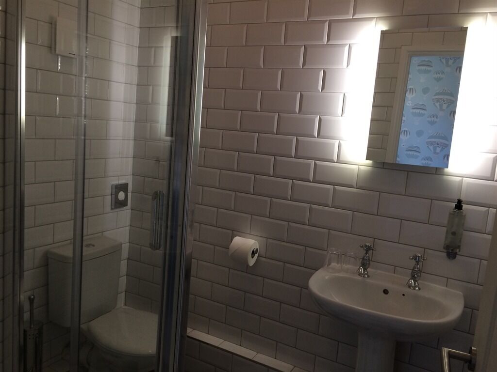 Un baño con cabina de ducha de vidrio, inodoro, lavabo con espejo y toallero.