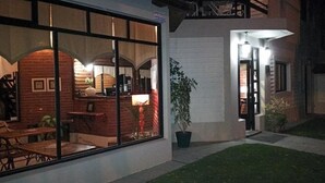 Un edificio con fachada de ladrillo, ventanas amplias y un pequeño espacio al aire libre con mesas y sillas.