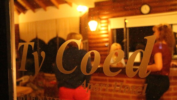 Un letrero de hotel con el nombre 'Ty Coed Apart Hotel' y un mensaje de bienvenida.