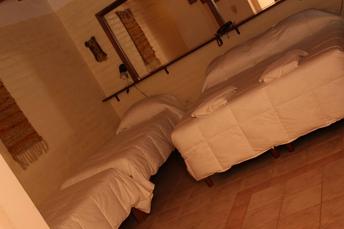 Ein Zimmer mit zwei Betten, einem Spiegel und einem an der Wand befestigten Regal.