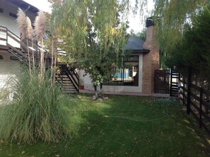 Ein Wohnhaus mit Backsteinfassade, einer sichtbaren Treppe und einem kleinen Garten mit Gras und Bäumen.