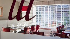 A restaurant interior with a modern design, featuring a dining area with tables and chairs, large windows with blinds, and a ceiling with a perforated pattern. - Camping As Cancelas (Santiago de Compostela)