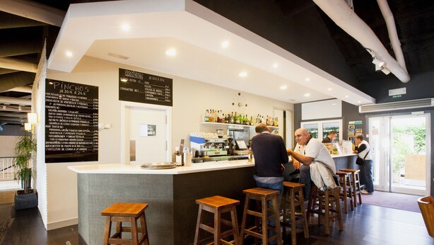 A bar area with stools, a counter, and a menu board. - Camping As Cancelas (Santiago de Compostela)