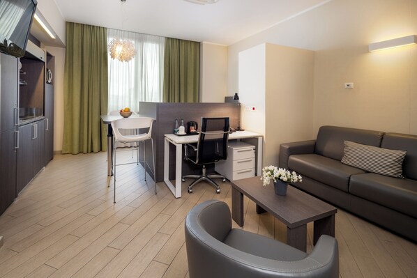 Una habitación de hotel moderna con kitchenette, comedor, espacio de trabajo y sala de estar.