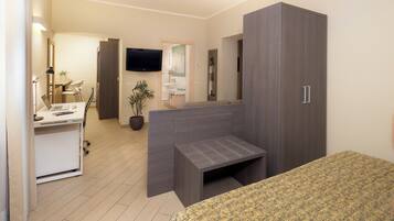 Een moderne slaapkamer met een bed, een bureau met een laptop, een televisie en een kledingkast.