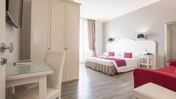 A hotel room with a bed, a desk, a chair, a wardrobe, and a bedside table.