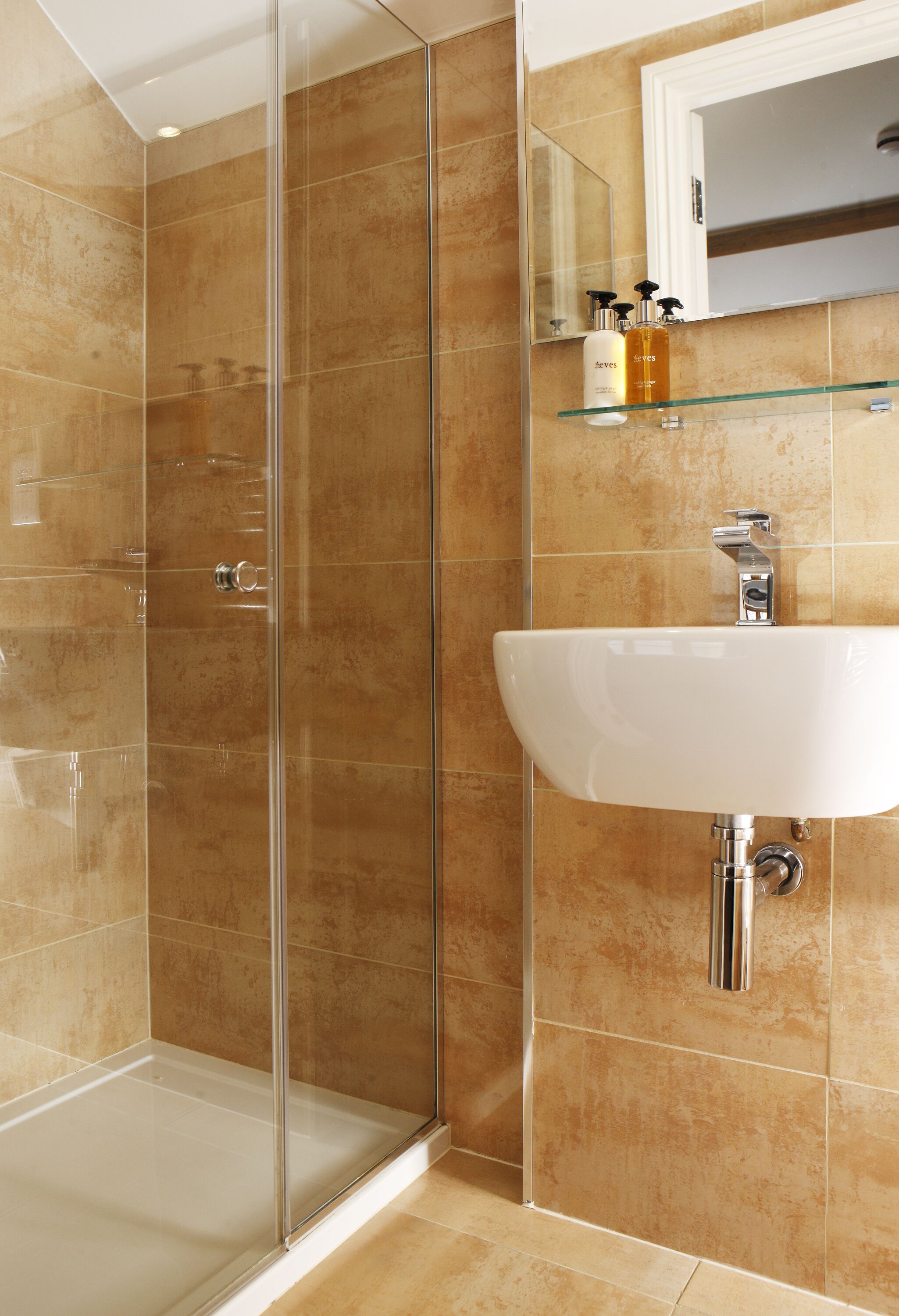 A bathroom with a glass shower enclosure, a white sink, and a mirror above it.