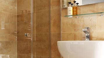 A bathroom with a glass shower enclosure, a white sink, and a mirror above it.