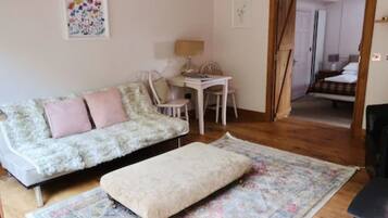 A cozy room with a sofa, a small table, and a chair. There is a door leading to another room.