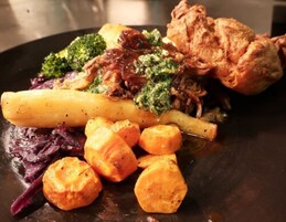 Un plato de comida con varias verduras y un trozo de pollo frito.