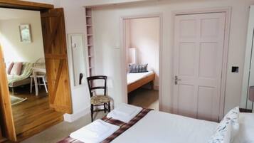 Un dormitorio con cama, una silla, un armario y una puerta que da a otra habitación.