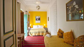 Une chambre d’hôtel avec un lit, un canapé, une moquette rouge et un tableau au mur.