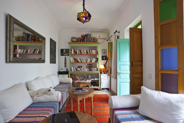 Un salon chaleureux avec un canapé, une petite table et une bibliothèque remplie de livres.