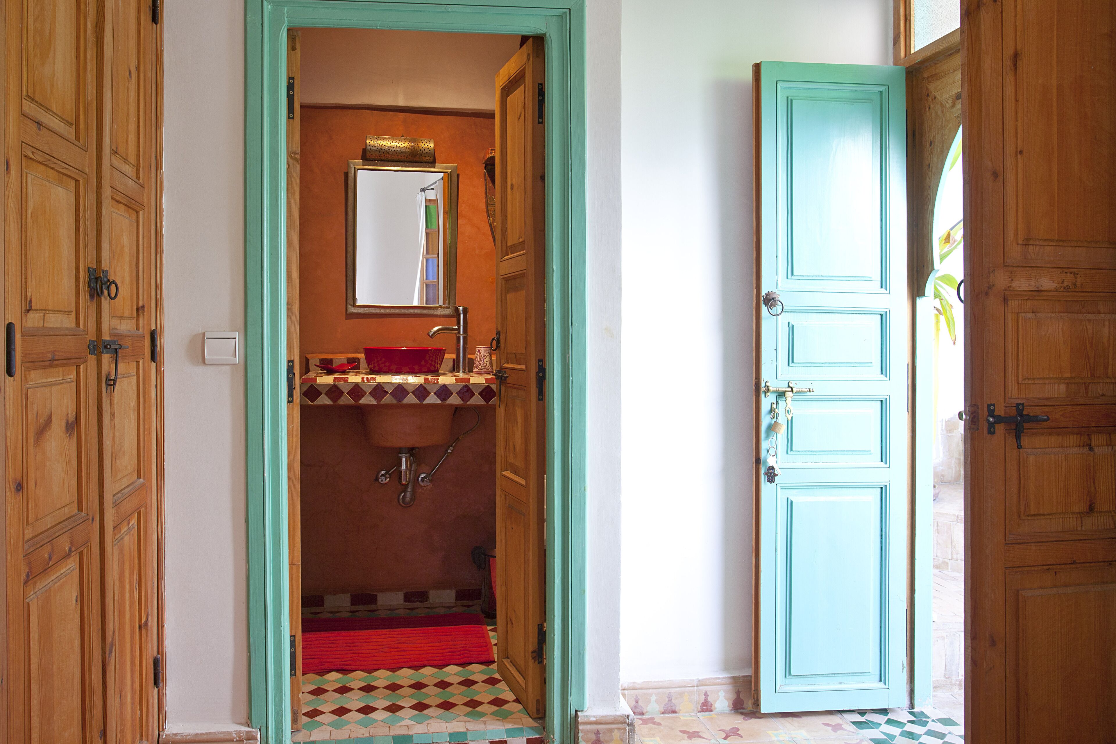 Une salle de bain avec une porte en bois, un lavabo et un miroir.