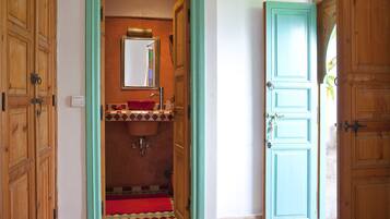 Une salle de bain avec une porte en bois, un lavabo et un miroir.