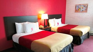 Une chambre d’hôtel avec deux lits, des murs rouges et une table de chevet avec une lampe.