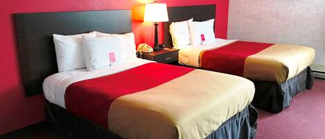 Une chambre d’hôtel avec deux lits, des murs rouges et une table de chevet avec une lampe.