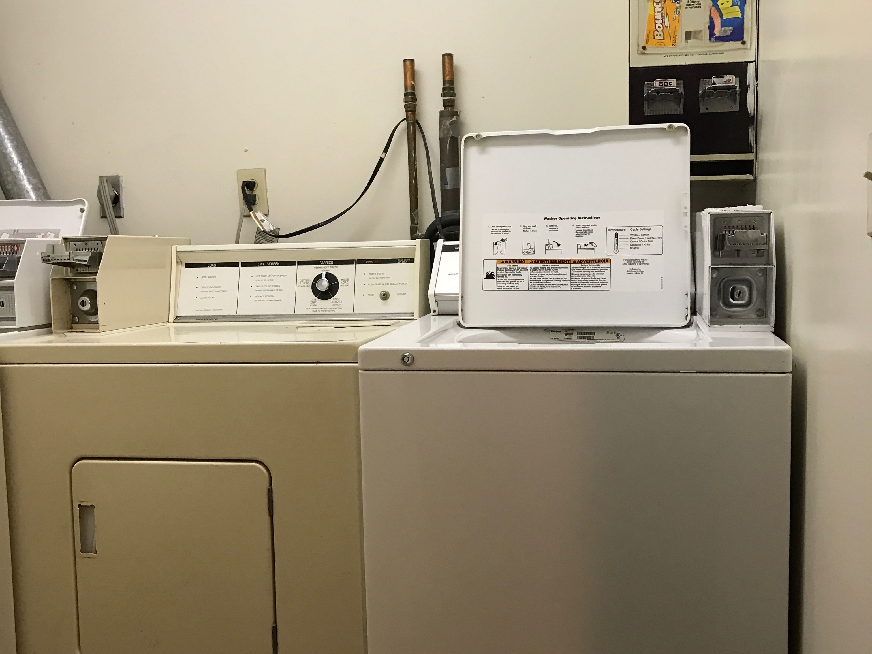 A laundry room with a washing machine, a dryer, and a utility panel with various controls and outlets.