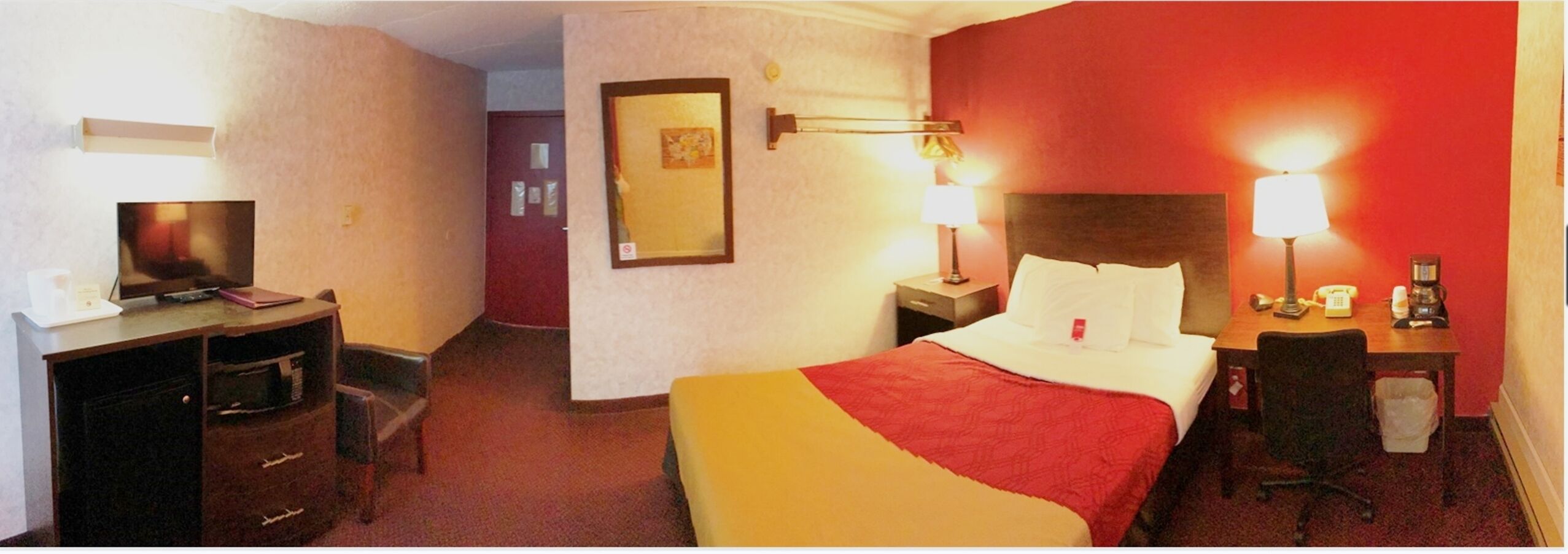 Une chambre d’hôtel équipée d’un lit, d’un bureau, d’une chaise et d’un téléviseur.