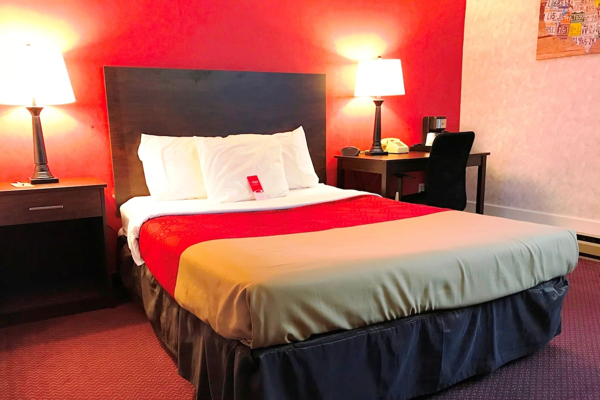 A hotel room with a large bed, two bedside lamps, a desk, and a chair.