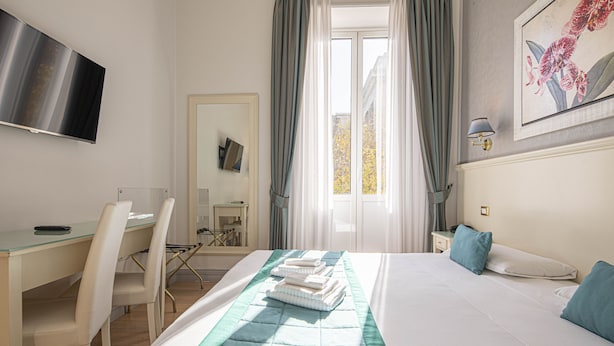 A hotel room with a bed, a desk, and a chair. - Residenza Castrense (Rome)