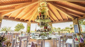 Un área de comedor al aire libre techada, con vigas de madera y mesas dispuestas para una comida.