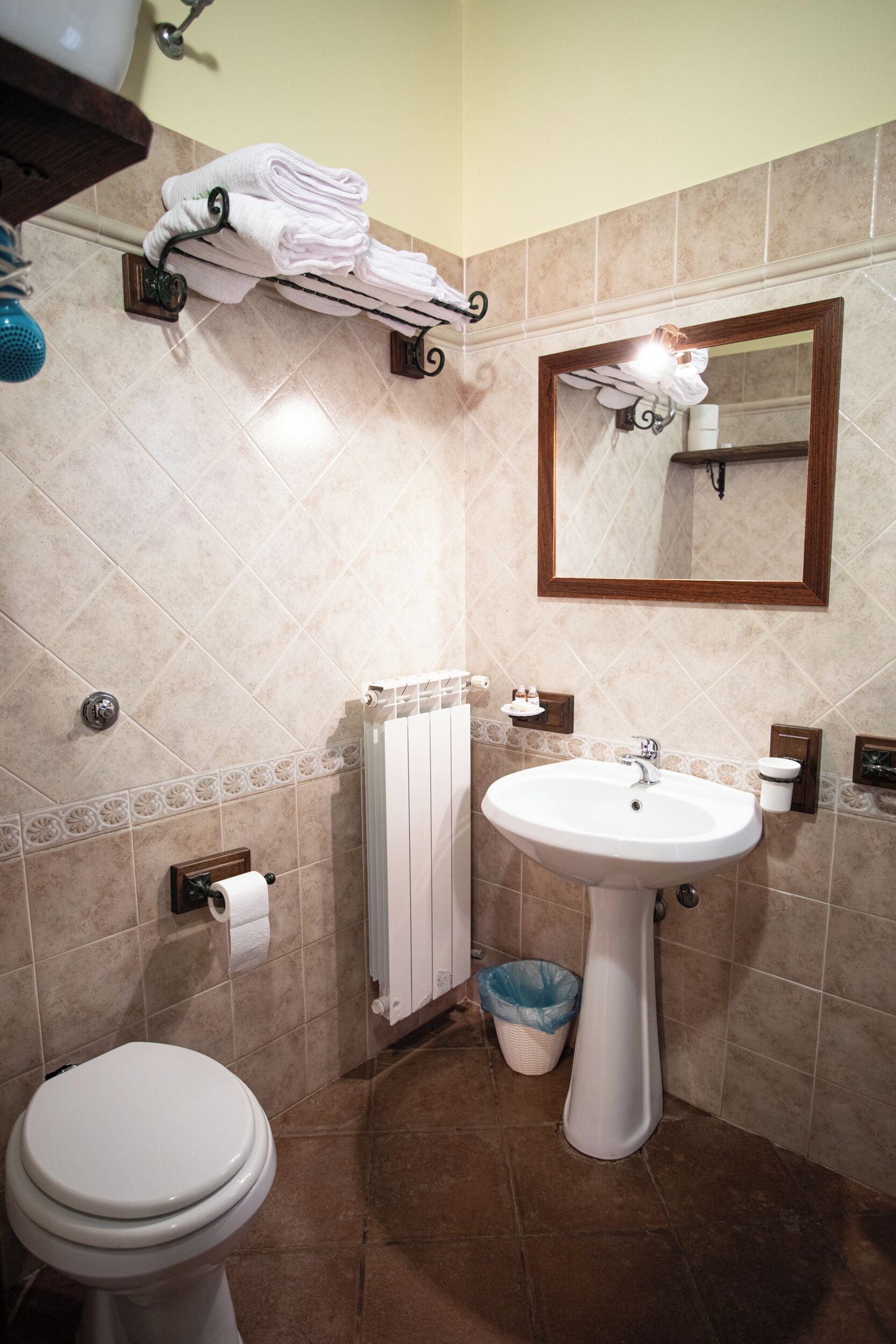 Ein Badezimmer mit einem weißen Waschbecken, einer Toilette und einem Handtuchhalter mit gefalteten Handtüchern.