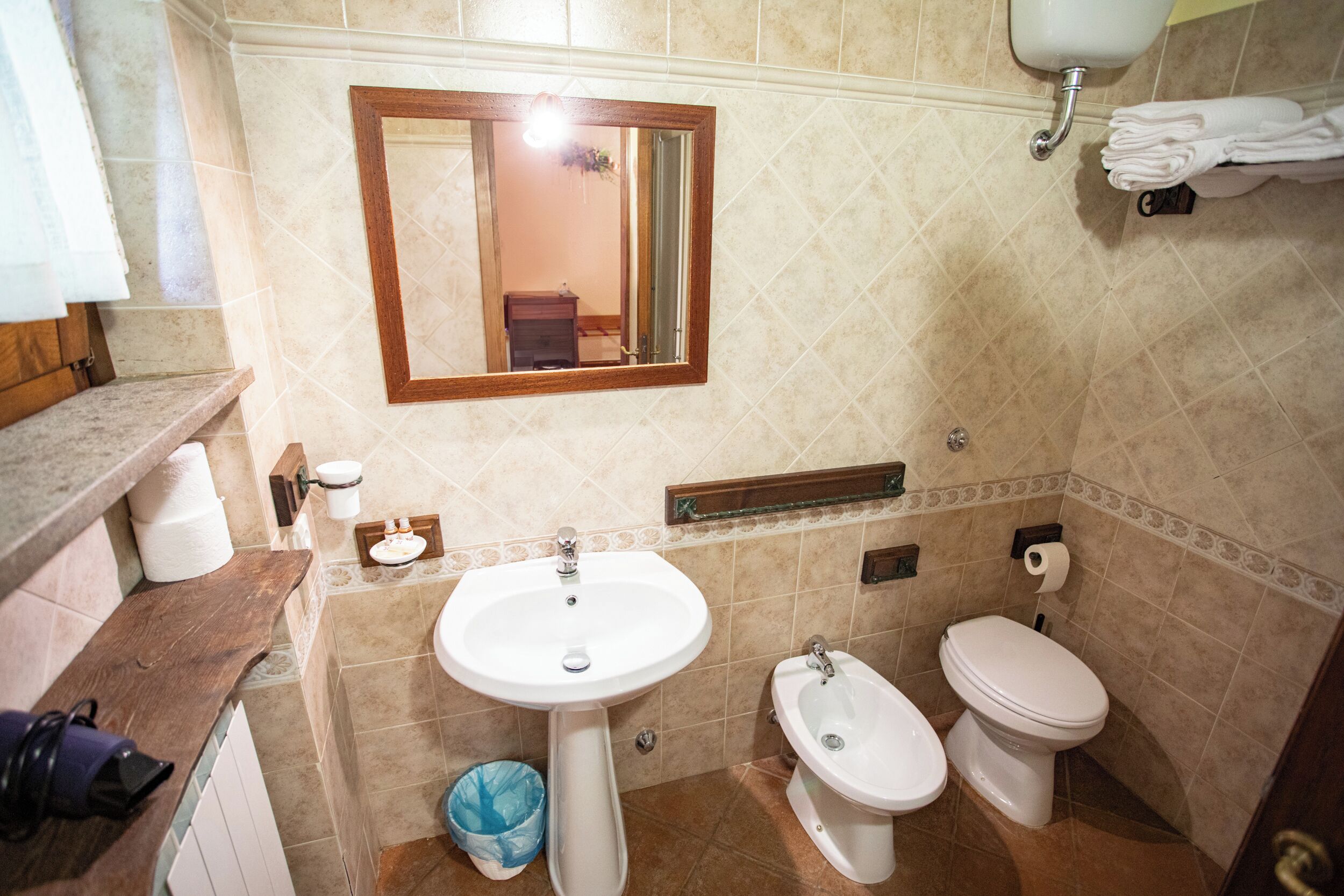 A bathroom with a sink, bidet, toilet, and a mirror.