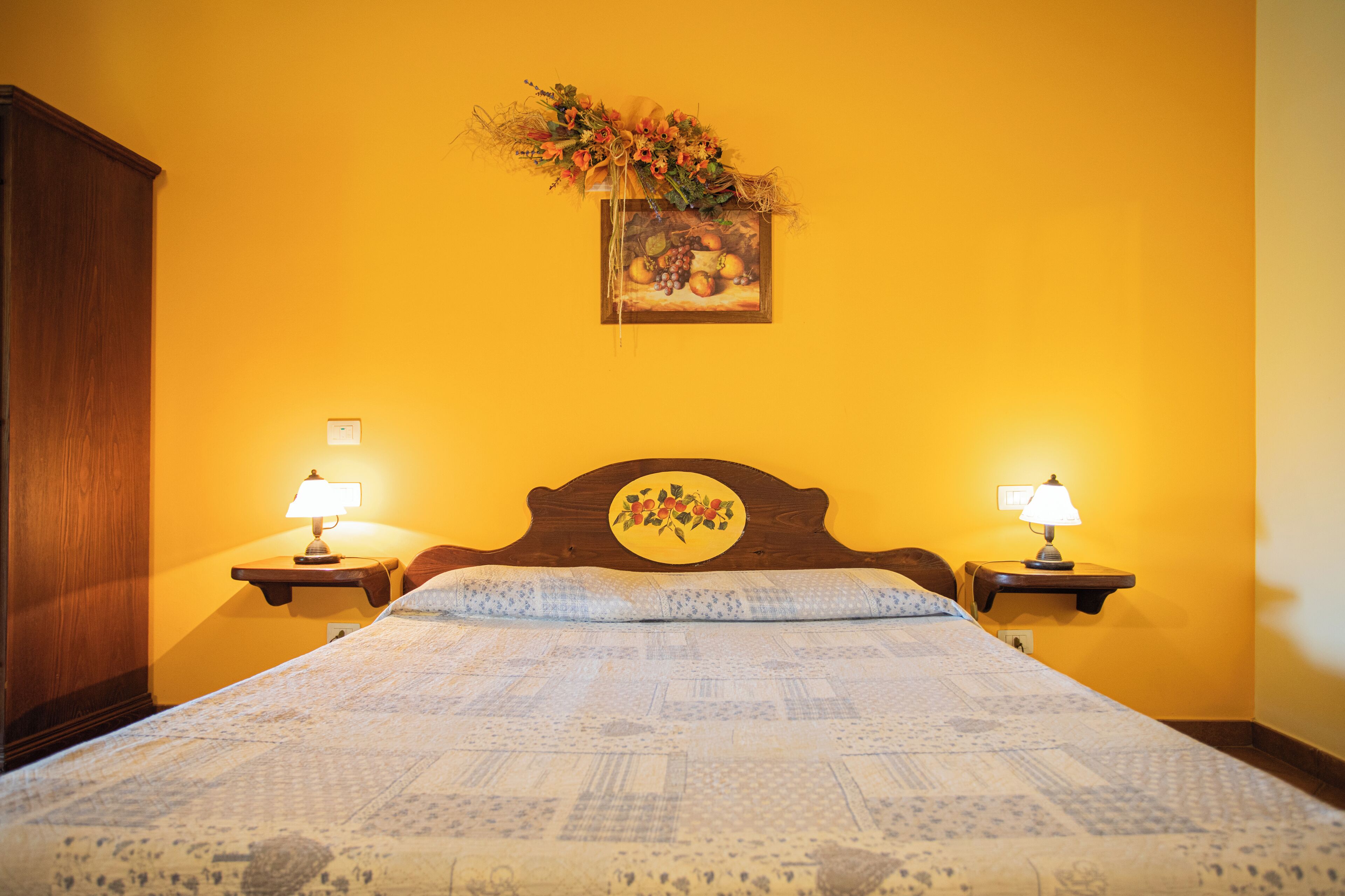Une chambre à coucher avec un grand lit, deux tables de chevet avec des lampes, une tête de lit en bois et un tableau accroché au mur.