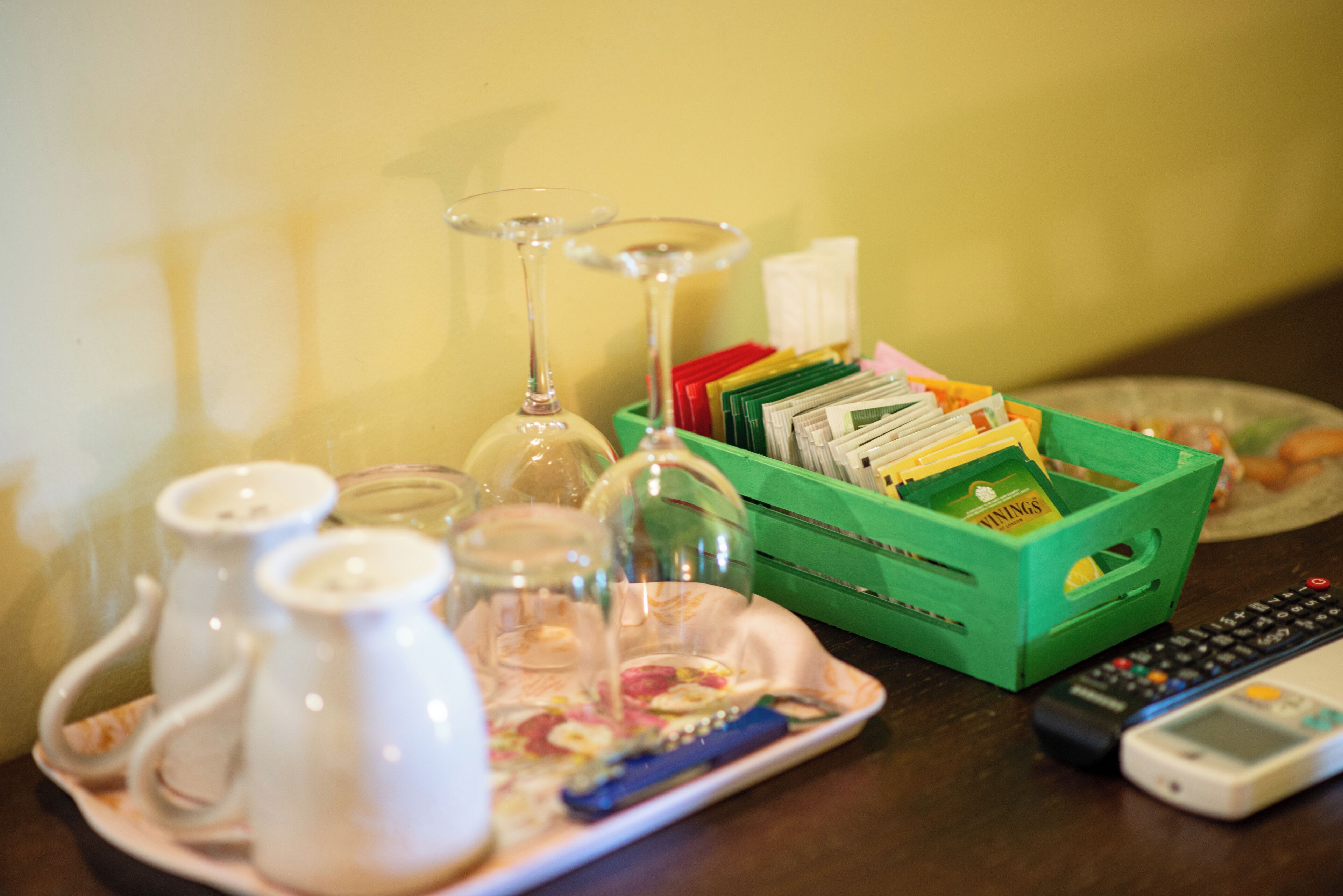 Une table avec une boîte verte contenant des en-cas, une télécommande et une assiette avec de la nourriture et des boissons.