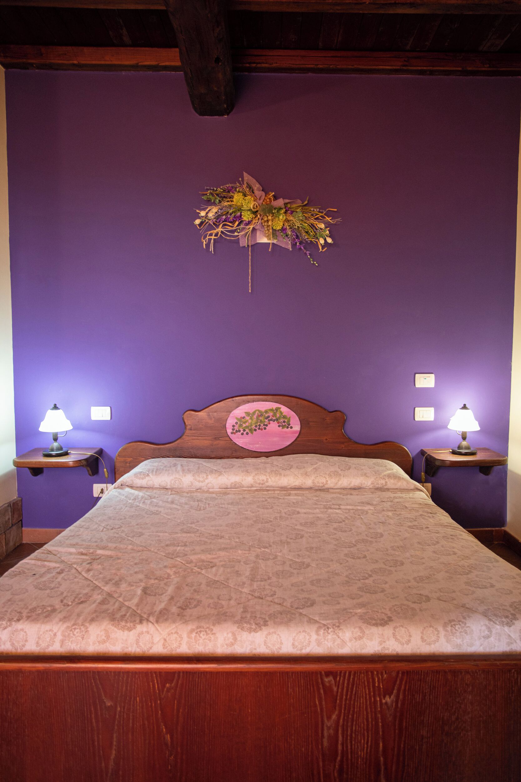 A bedroom with a wooden bed, purple walls, and two bedside lamps.