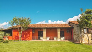 Un edificio de dos pisos con fachada roja, detalles de piedra y tejado de tejas.