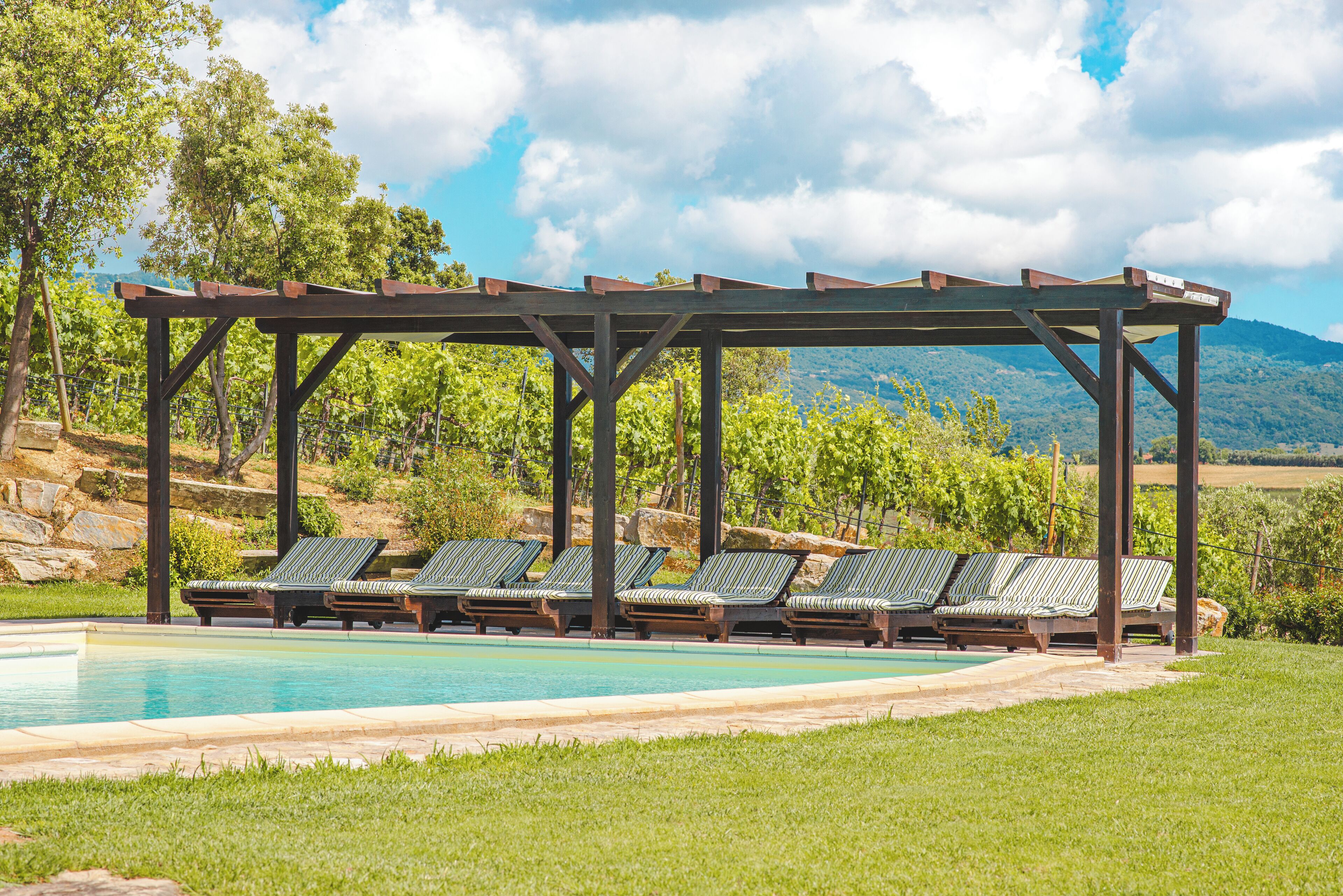 Ein Poolbereich mit einer Pergola und Liegestühlen.