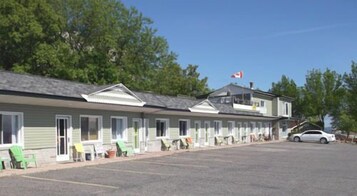 A motel with a row of single-story rooms, a parking lot, and a flag on the roof.