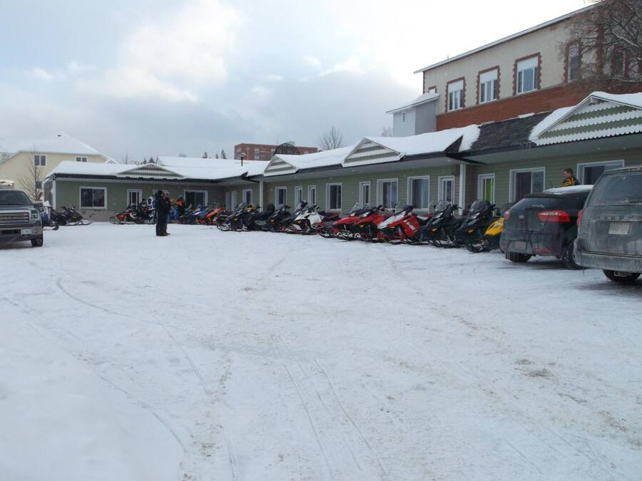 Un estacionamiento cubierto de nieve con varias motos de nieve alineadas.