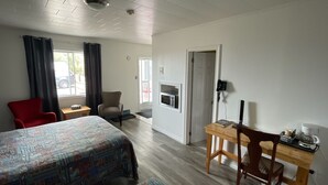 Una habitación de hotel con cama, escritorio, silla, microondas y teléfono.