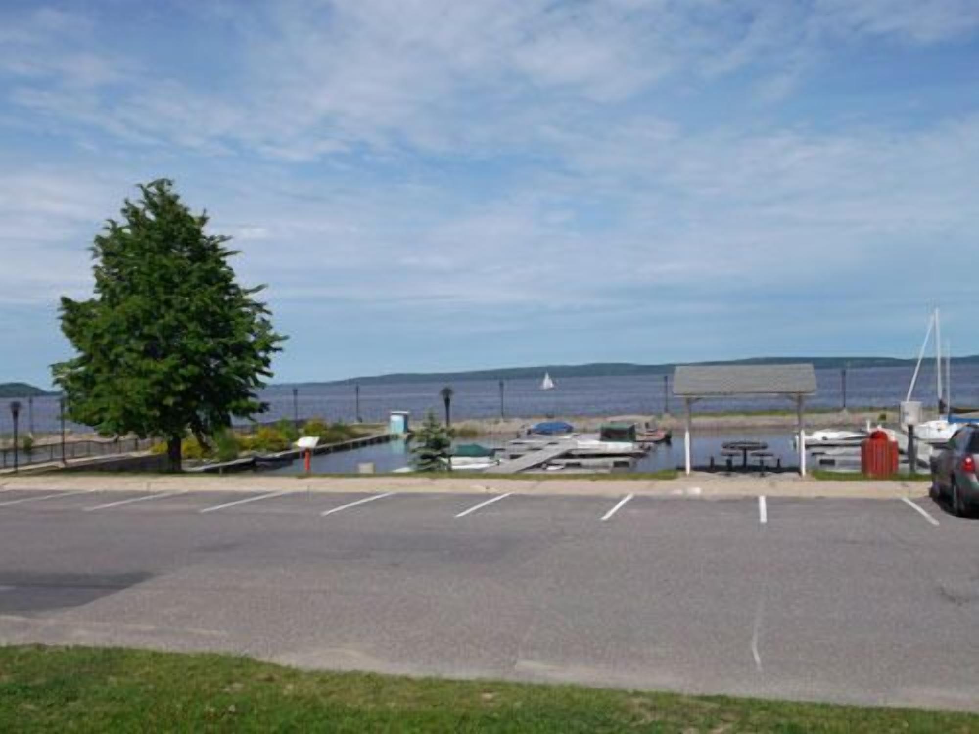 A parking lot with a view of the sea, a picnic table, and a covered area.