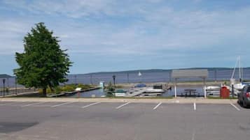 A parking lot with a view of the sea, a picnic table, and a covered area.