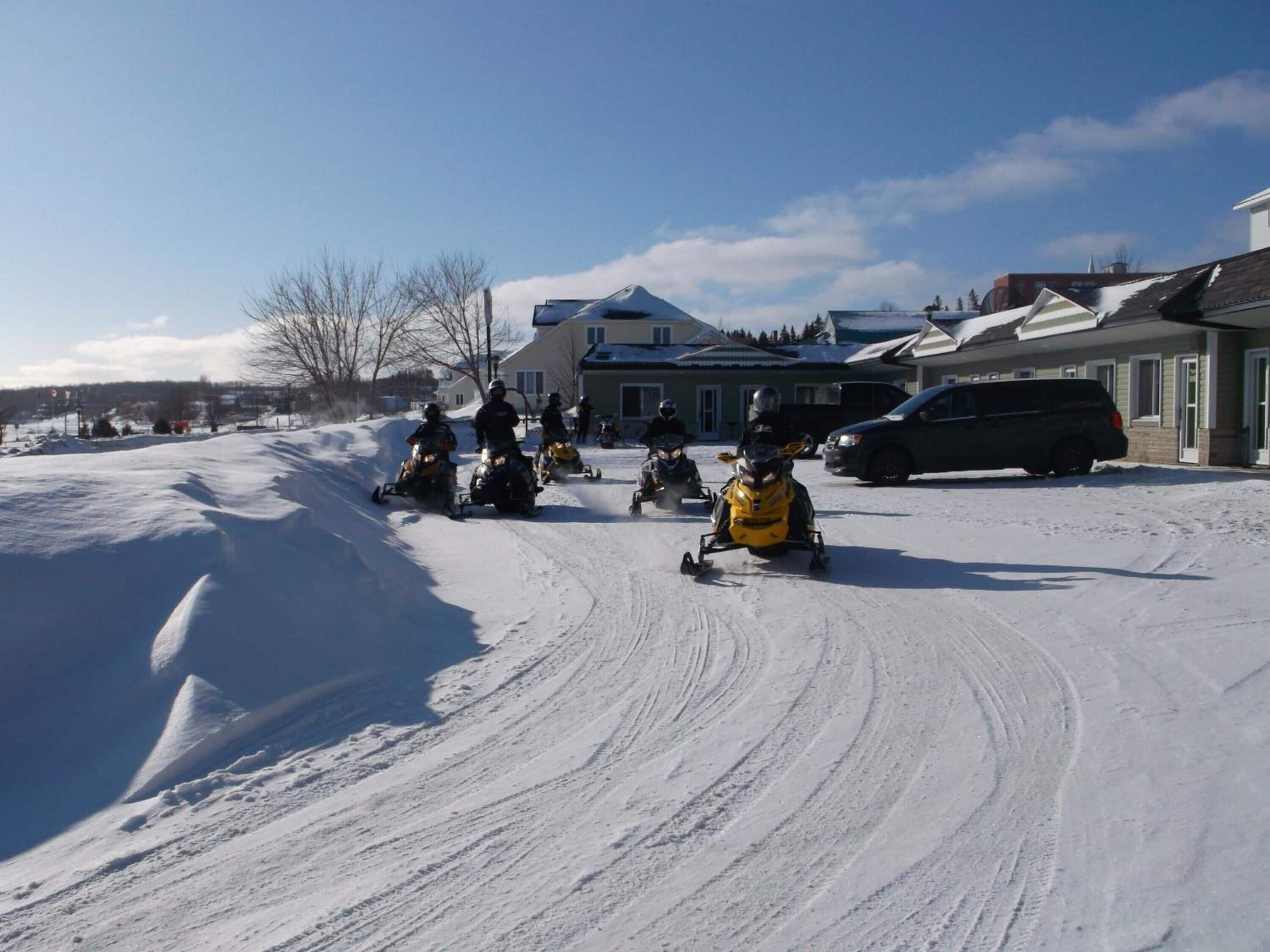 A snowy residential area with houses and a van parked in the driveway.