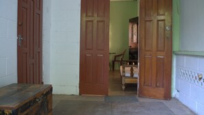 A hallway with two wooden doors, a bench, and a chair. - Port Lodge (Port of Spain)
