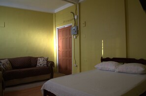 A room with a bed, a couch, and a door. - Port Lodge (Port of Spain)