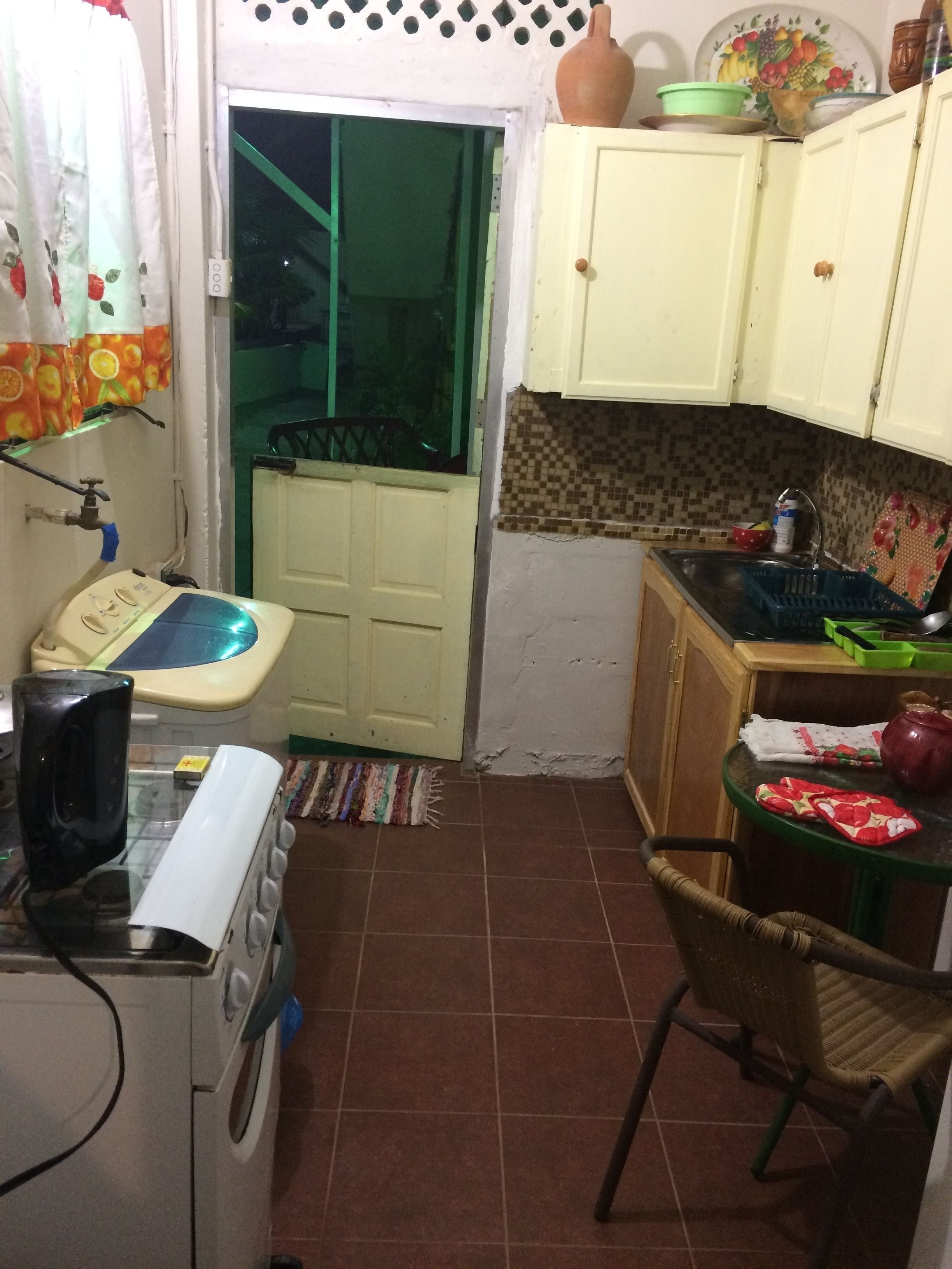 A compact kitchen with a washing machine, a small table, and a chair.