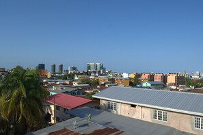 A cityscape with various buildings, including a prominent skyscraper in the distance. - Port Lodge (Port of Spain)