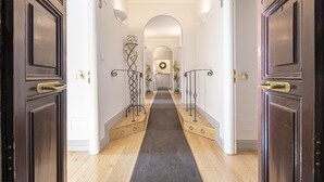 A hallway with wooden floors, dark wooden doors, and a central archway leading to another room. - Suite Castrense (Rome)