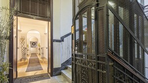 A hotel entrance with a metal gate, a carpeted entrance, and a staircase leading to the upper floors. - Suite Castrense (Rome)